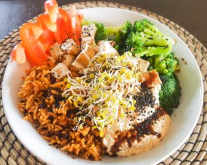 Bowl mit Reis, Paprika, Brokkoli, Tofu, Hummus und Sprossen